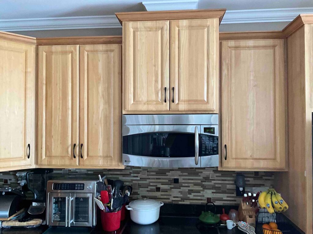 Before image of a kitchen showcasing the microwave area with dated orange cabinets