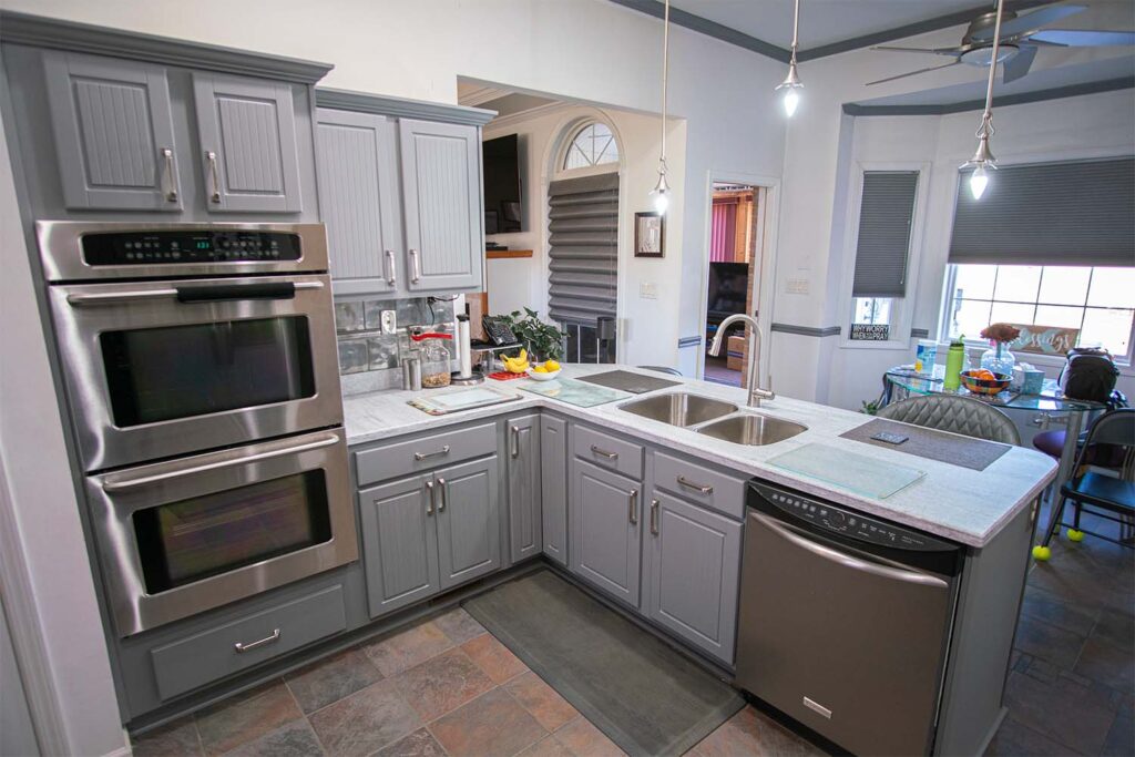 Refaced kitchen sink and oven area with Victory style doors and drawer fronts in dust grey after cabinet refacing.