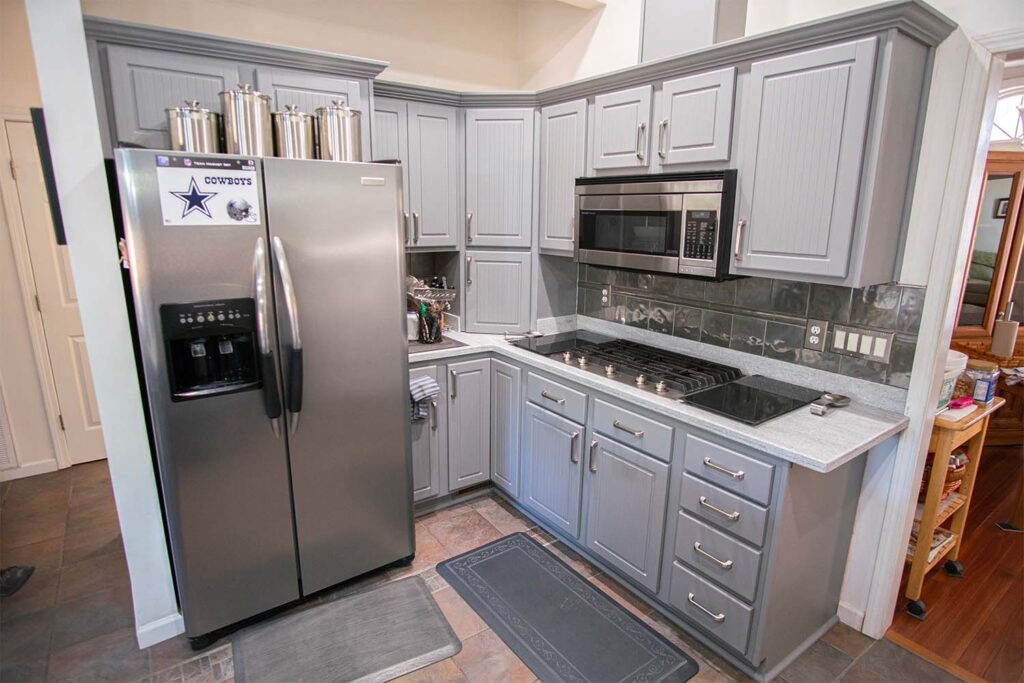 Refaced kitchen stove and fridge area with Victory style doors and drawer fronts in dust grey after cabinet refacing.