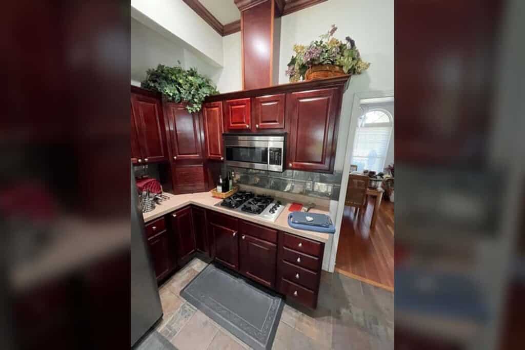 Stove area of a kitchen with dated red cabinets before cabinet refacing.