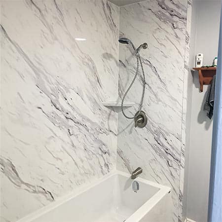 Acrylic bathtub with acrylic walls mimicking marble, showcasing a modern bathroom design.