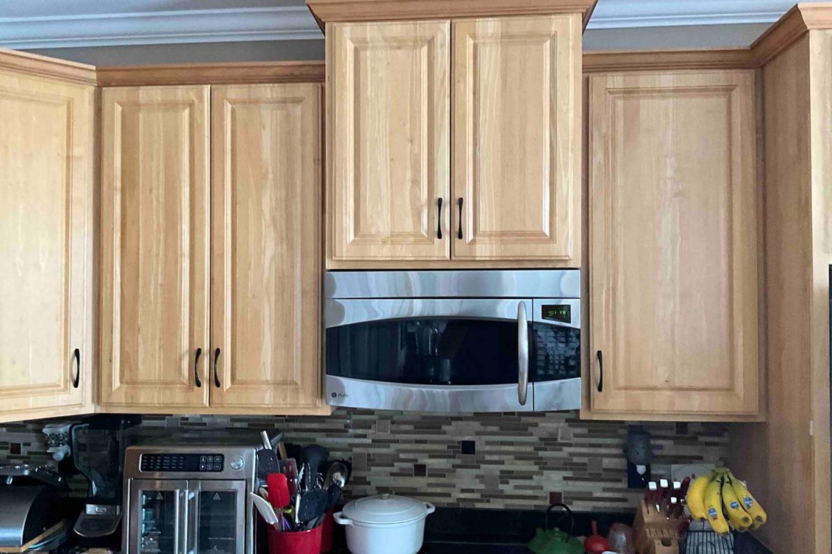 Before image of a kitchen showcasing the microwave area with dated orange cabinets