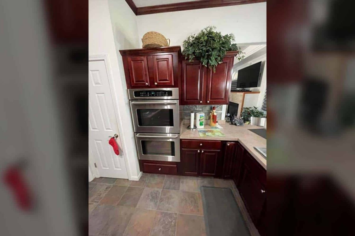 Oven area of a kitchen with dated red cabinets before cabinet refacing.